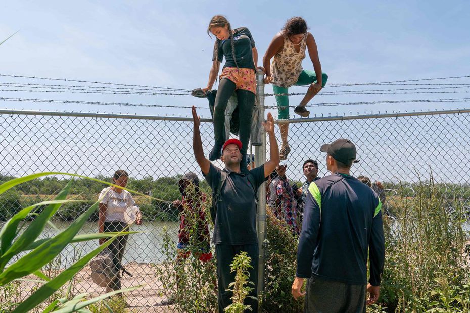 Migrantes  se ayudan a trepar la cerca que separa a México de Estados Unidos, en Eagle Pass, Texas. FOTO: SUZANNE CORDEIRO. AFP