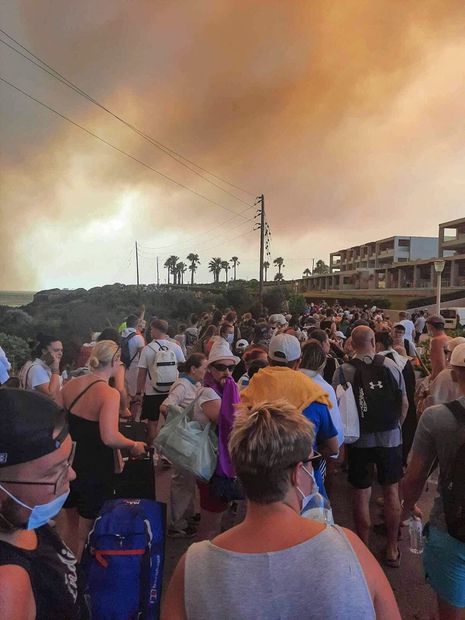 Los turistas son evacuados de los hoteles durante un incendio forestal en la isla griega de Rodas el 22 de julio de 2023. Tres barcos de guardacostas dirigían a más de 20 embarcaciones en un esfuerzo de evacuación de emergencia para rescatar a personas de la zona. Foto: AFP