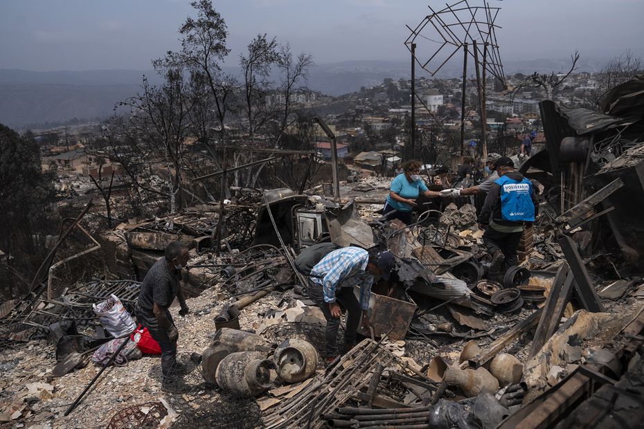 Personas retiran escombros desde una casa en el sector de Achupallas afectada por incendios forestales de Viña del Mar, Región de Valparaiso. Foto: EFE