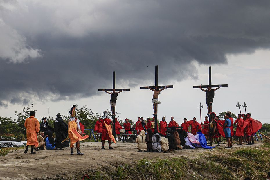 Ruben Enaje, center, remains on the cross flanked by two other devotees during a reenactment of Jesus Christ's sufferings as part of Good Friday rituals in San Pedro Cutud, north of Manila, Philippines, Friday, March 29, 2024. The Filipino villager was nailed to a wooden cross for the 35th time to reenact Jesus Christ’s suffering in a brutal Good Friday tradition he said he would devote to pray for peace in Ukraine, Gaza and the disputed South China Sea. (AP Photo/Gerard V. Carreon)