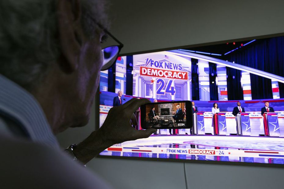 Televidente sigue el debate republicano y la entrevista a Trump al mismo tiempo. Foto: EFE