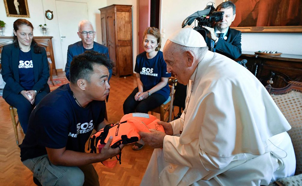 El papa Francisco recibe un chaleco salvavidas de manos de un miembro de SOS Mediterranee, una ONG europea que rescata a migrantes en el mar. Foto: AFP