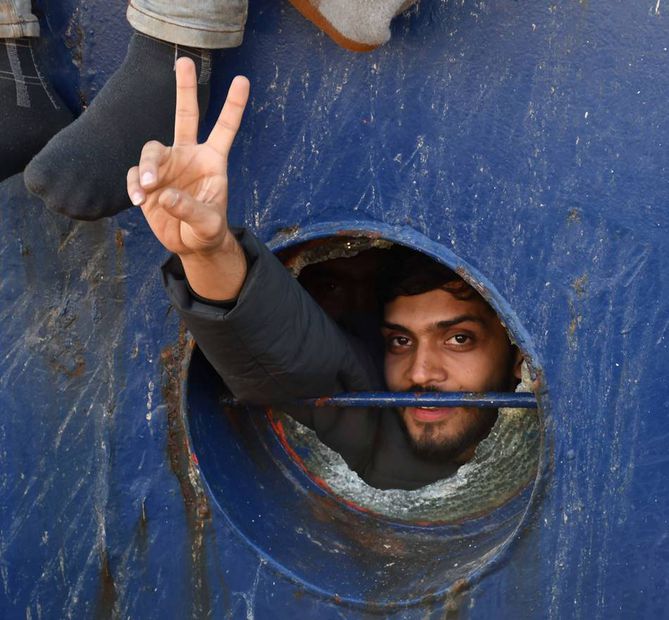 Migrante saluda con una V mientras llega al puerto de Catania, en Italia. Foto: EFE