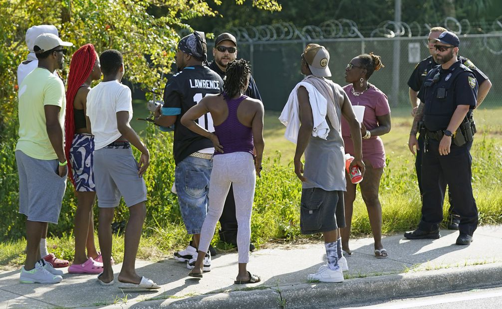 Los residentes hablan con agentes de Jacksonville cerca de la escena de un tiroteo masivo en una tienda Dollar General, el sábado 26 de agosto. Foto: AP