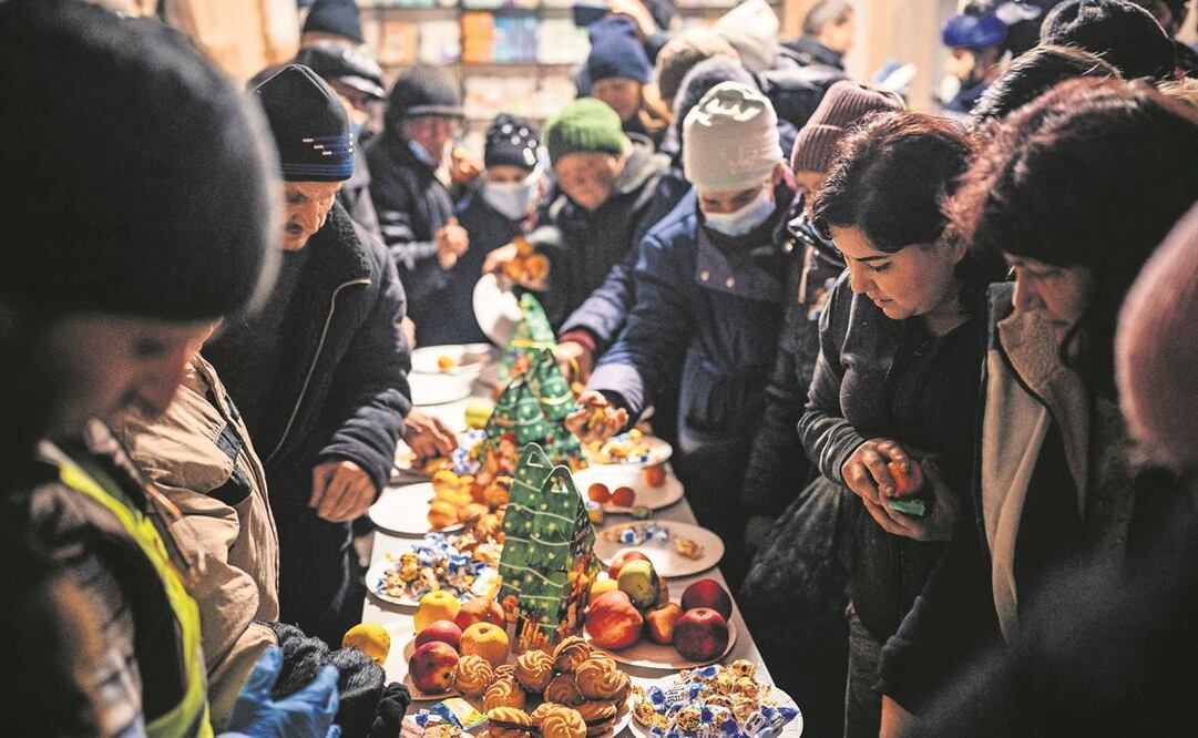 Ucranianos, alrededor de una mesa navideña para servirse pequeños pasteles y frutas, en un centro de ayuda humanitaria en Bakhmut. Foto : Dimitar Dilkoff/ AFP