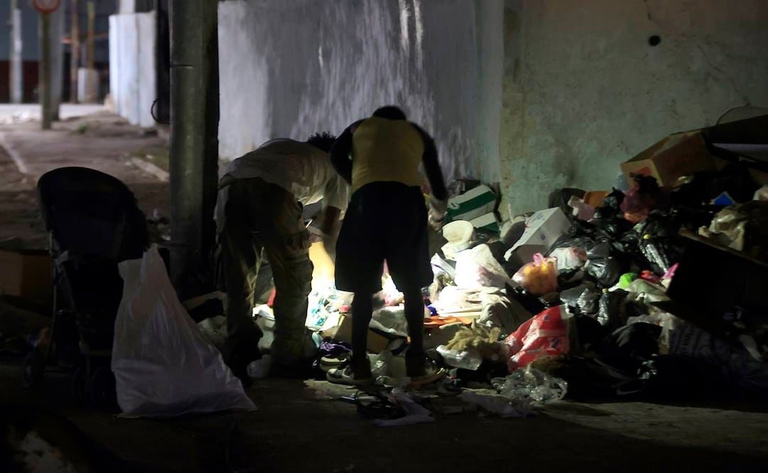 Personas revisan basura durante un apagón este jueves en La Habana (Cuba). Los prolongados apagones en Cuba afectarán este sábado de forma simultánea hasta el 67% del país, cuando ocurra el mayor corte del suministro en el momento de más demanda (tarde-noche), según datos de la estatal Unión Eléctrica (UNE), elaborados por EFE. Foto: EFE