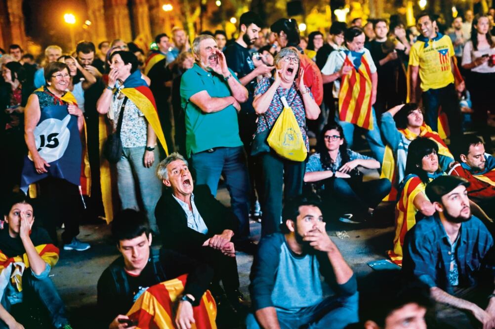Independentistas catalanes reaccionan al escuchar el discurso en el que se suspendió la declaratoria de “República independiente”', en Barcelona. (PAU BARRENA. AFP)