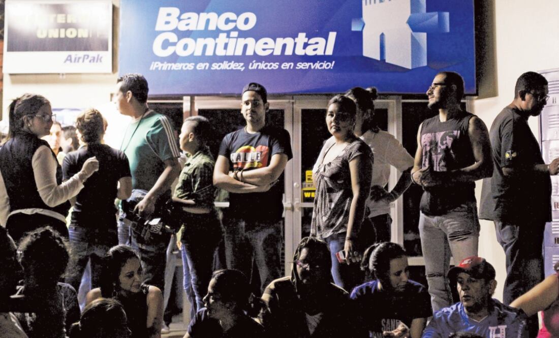 Empleados del Banco Continental, que la semana pasada entró al listado criminal que el Departamento del Tesoro de Estados Unidos elabora desde 2000, permanecen afuera de una de sus sucursales en Honduras (JORGE CABRERA. REUTERS)
