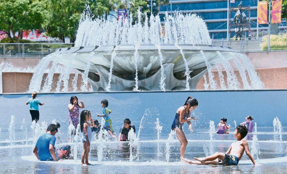 Alivio. Niños se refrescan en una fuente en Los Ángeles, afectada por una ola de calor. (FREDERIC J. BROWN. AFP)