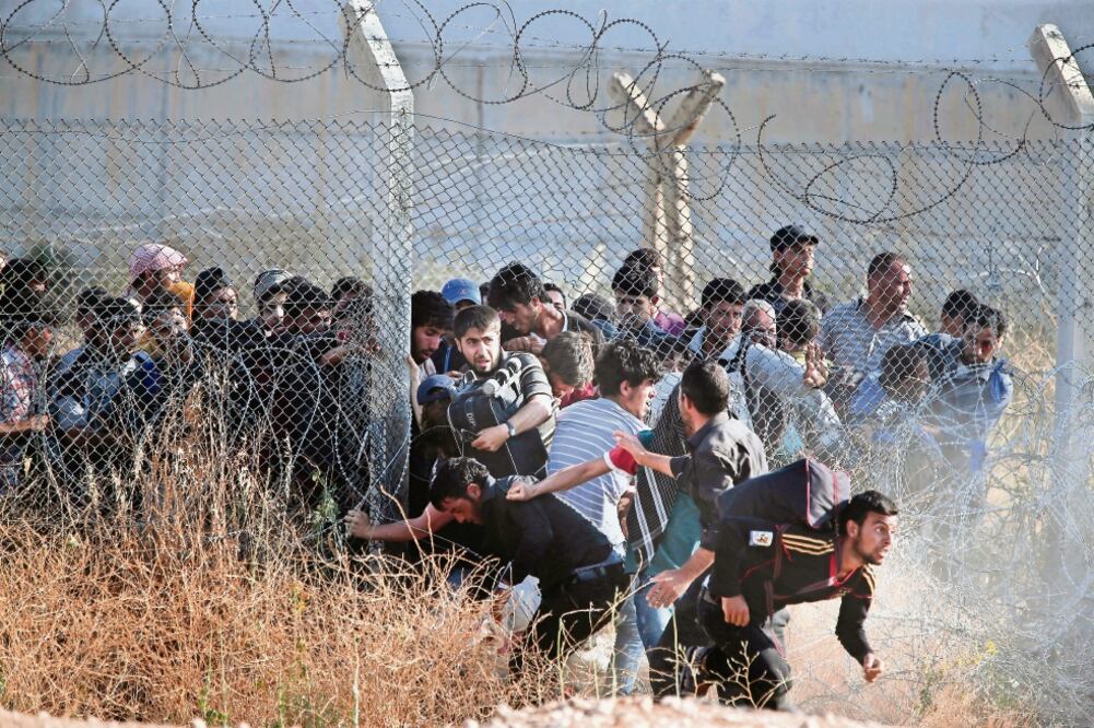 Refugiados sirios ingresan a suelo turco tras destruir una cerca que les impedía el paso, en junio de 2015. Expertos afirman que con el acuerdo entre la UE y Ankara la crisis migratoria se “externalizó” (ARCHIVO. AP)
