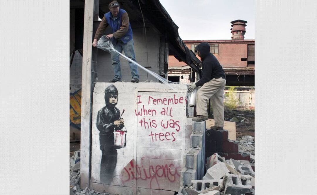 En el mural se ve un niño con un cubo de pintura roja y un pincel, junto a un mensaje que dice "Recuerdo cuando todo esto eran árboles". FOTO: AP.