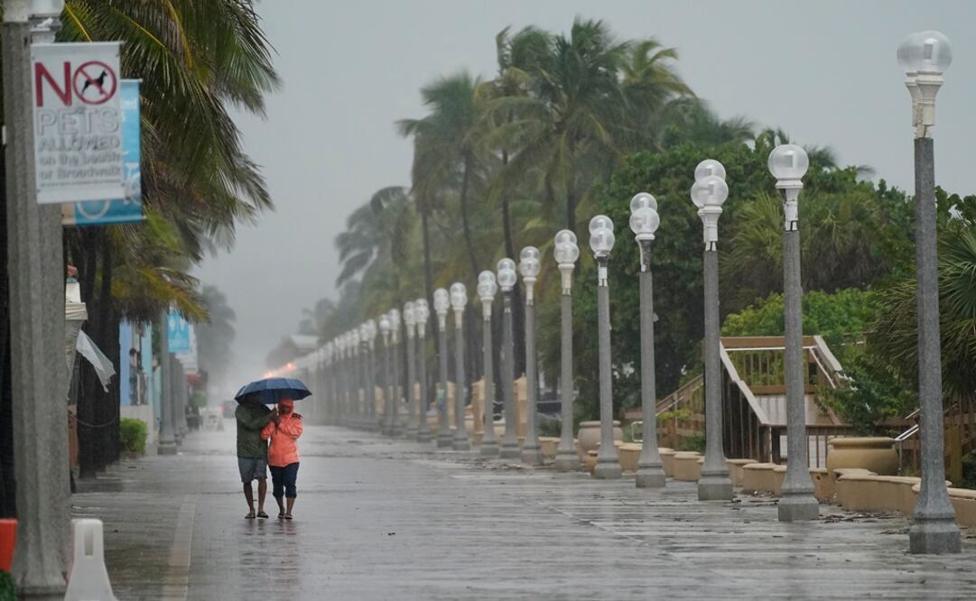 Un par de bañistas caminan por Hollywood Beach Broadwalk, mientras las condiciones se deterioran con la llegada del huracán Nicole. Foto: AP 