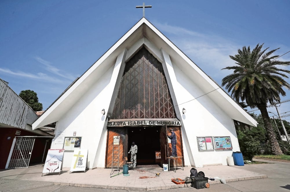 Personas trabajaban ayer en la parroquia Santa Isabel de Hungría, en donde vándalos lanzaron un paño impregnado con combustible y luego le aplicaron fuego, provocando un incendio que fue controlado por los bomberos en Santiago. (MARIO RUIZ. EFE)