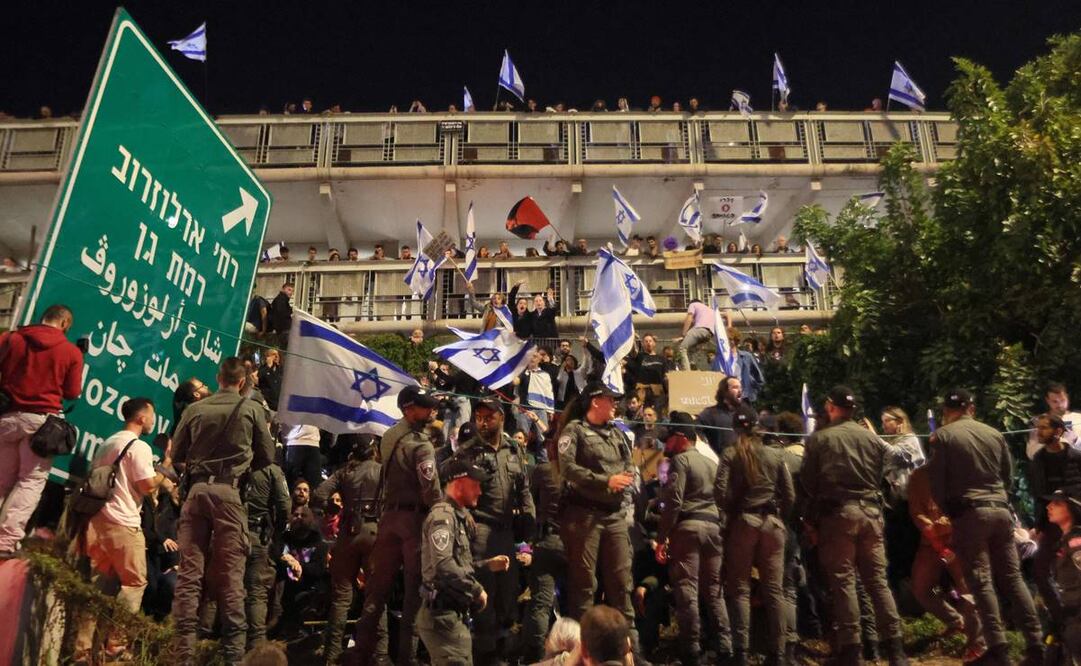 Los miembros de la seguridad israelí se despliegan mientras los manifestantes levantan banderas nacionales durante una protesta. Foto:  Jack Guez/AFP 