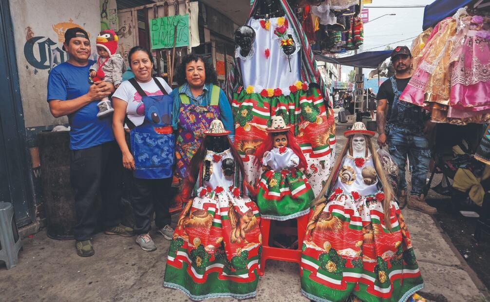 Familia devota a la Santa Muerte visitó el altar en el barrio de Tepito y como manda colocó vestidos con los colores patrios a sus niñas blancas. Foto: Luis Camacho/ EL UNIVERSAL