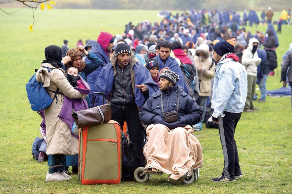 Refugiados esperan la llegada de autobuses en la frontera con Austria en la localidad de Wegscheid, Alemania, donde enfrentan frío y hambre (SEBASTIAN KAHNERT. EFE)