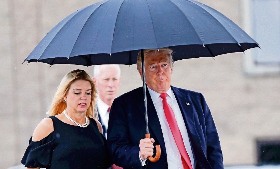 Donald Trump, camina bajo la lluvia junto con la secretaria de Justicia de Florida, Pam Bondi, hacia un acto de campaña, ayer, en Tampa, Florida. Foto: AP/Archivo