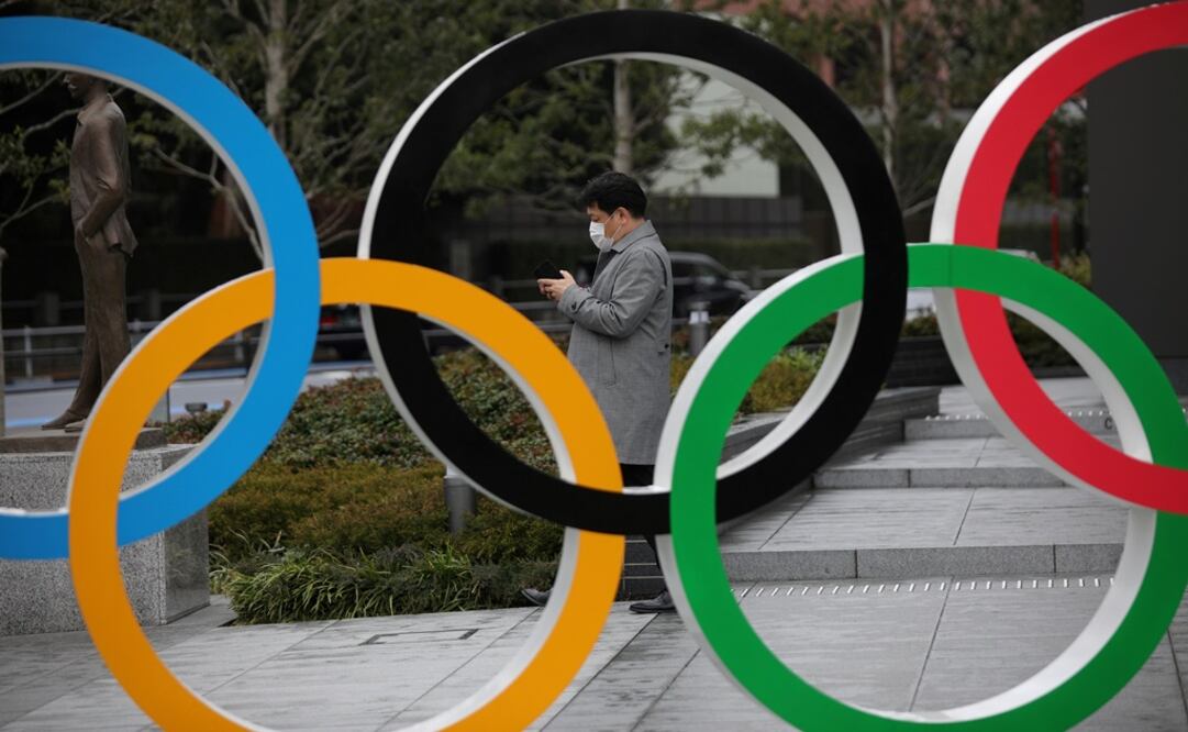 A man wearing protective face mask, following the outbreak of the coronavirus, looks at his mobile phone next to The Olympic rings in front of the Japan Olympics Museum - Photo: Stoyan Nenov/REUTERS