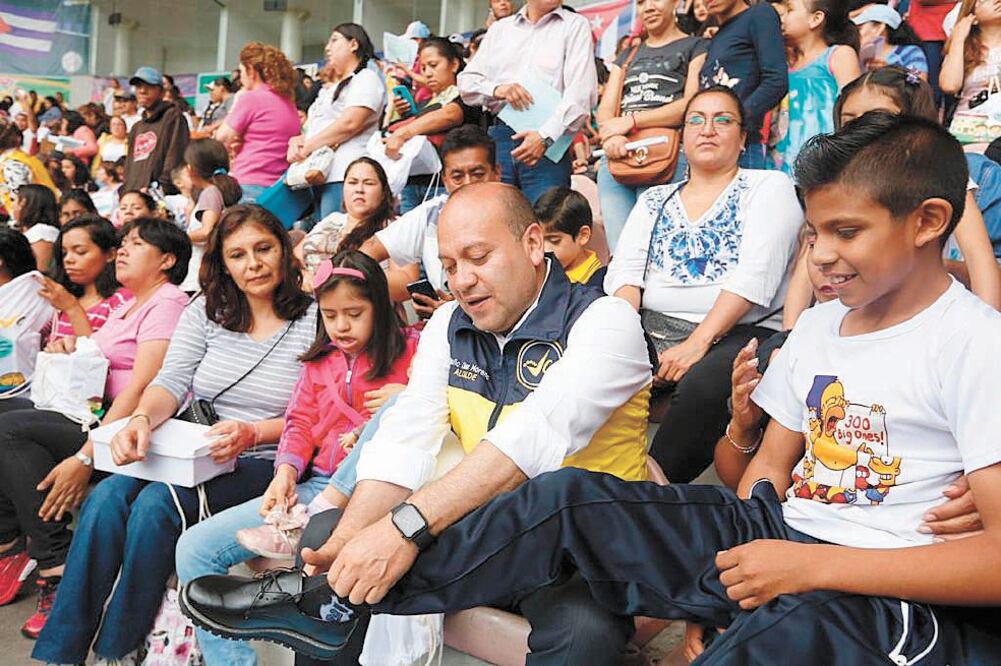 Julio César Moreno Rivera, edil de Venustiano Carranza, entregó los primero pares de zapatos e incluso se los colocó a algunos niños. Foto/ESPECIAL