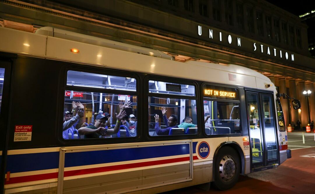 Inmigrantes saludan cuando sale un autobús para llevarlos a un centro de refugiados en las afueras de Union Station en Chicago. Foto: AP