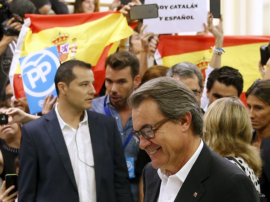 Un joven sacó una bandera de España y la agitó tras el jefe del Ejecutivo catalán mientras emitía su voto (REUTERS)