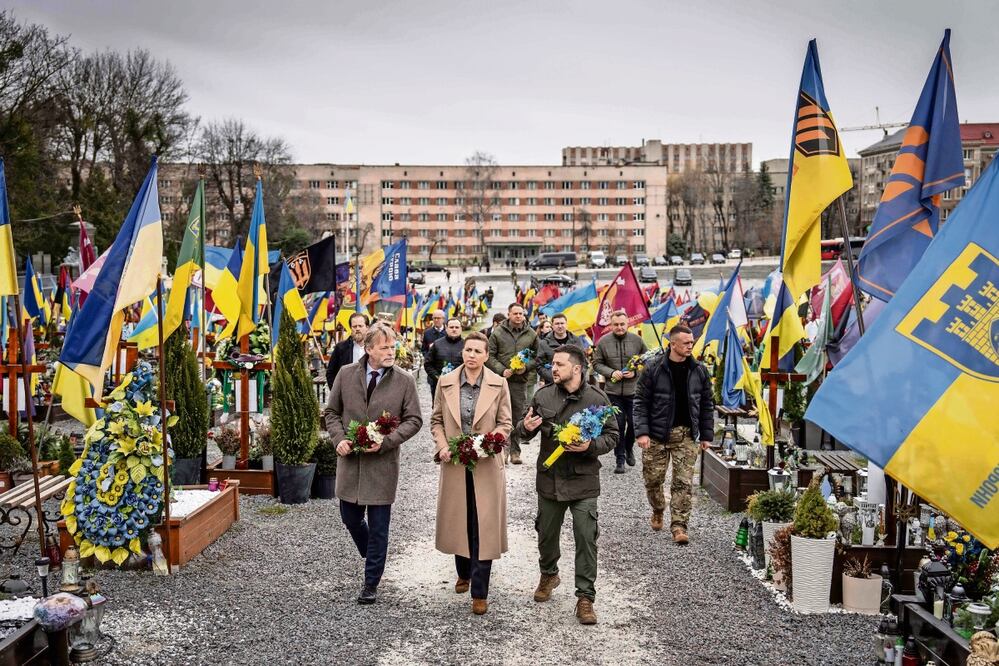 La primera ministra de Dinamarca, Mette Frederiksen (centro), su esposo Bo Tengberg (izq.), y el presidente de Ucrania, Volodimir Zelensky (der.), durante una ceremonia conmemorativa en Lviv. Foto: AFP
