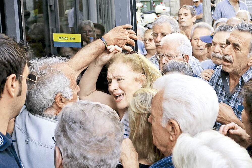 Una jubilada intenta entrar a una sucursal del Banco Nacional para recibir parte de su pensión, en la ciudad de Iraklio, en la isla de Creta. El “corralito” cumplió ayer 11 días (STEFANOS RAPANIS. REUTERS)