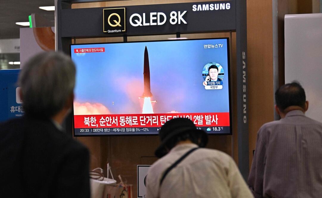 La gente mira una pantalla de televisión que muestra una transmisión de noticias con imágenes de archivo de una prueba de misiles de Corea del Norte. Foto: AFP