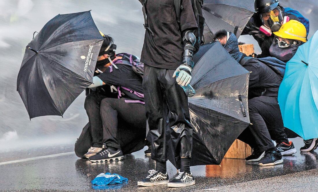 Manifestantes se enfrentaron a la policía, que disparó con cañones de agua afuera de la sede del gobierno en Hong Kong. Foto/ISAAC LAWRENCE. AFP