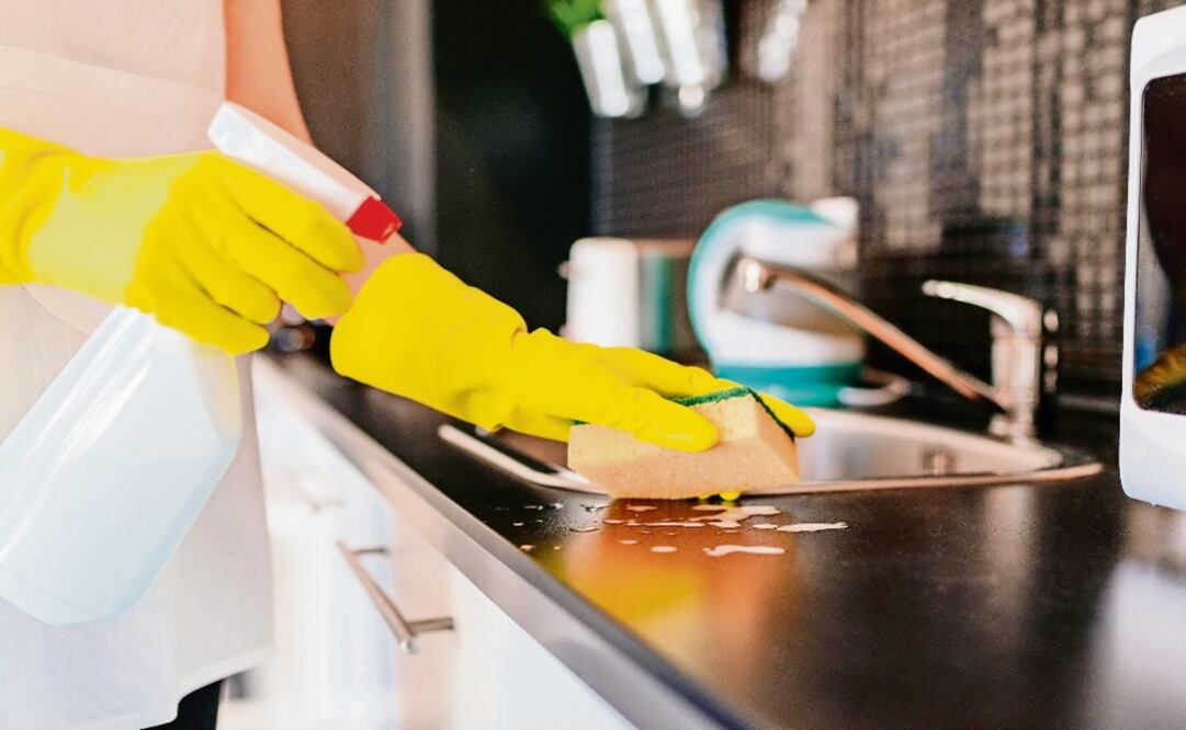 Woman cleaning kitchen cabinets with sponge and spray cleaner - Photo: Daniel Jedzura/EL UNIVERSAL