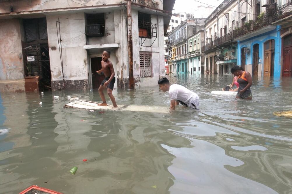 Un niño “su rfeó ” sobre una puerta de madera en el agua anegada en las calles de La Habana, luego del paso del huracán Irma por la isla (REUTERS)