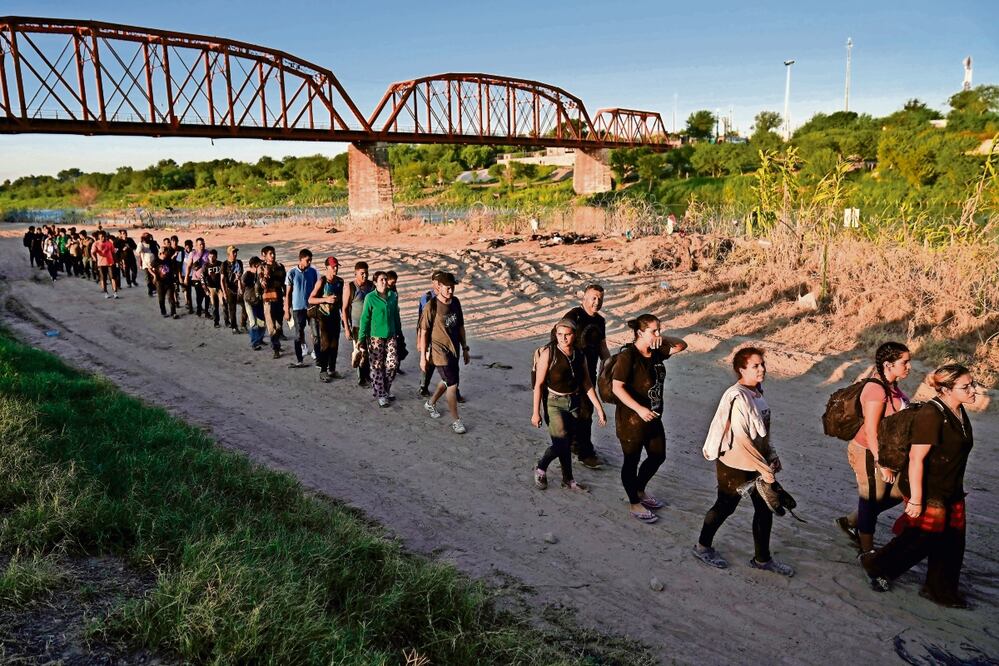 Migrantes que cruzaron el río Bravo y entraron a Estados Unidos desde México, al hacer fila para ser procesados por las autoridades fronterizas en Eagle Pass, Texas. Foto: AP
