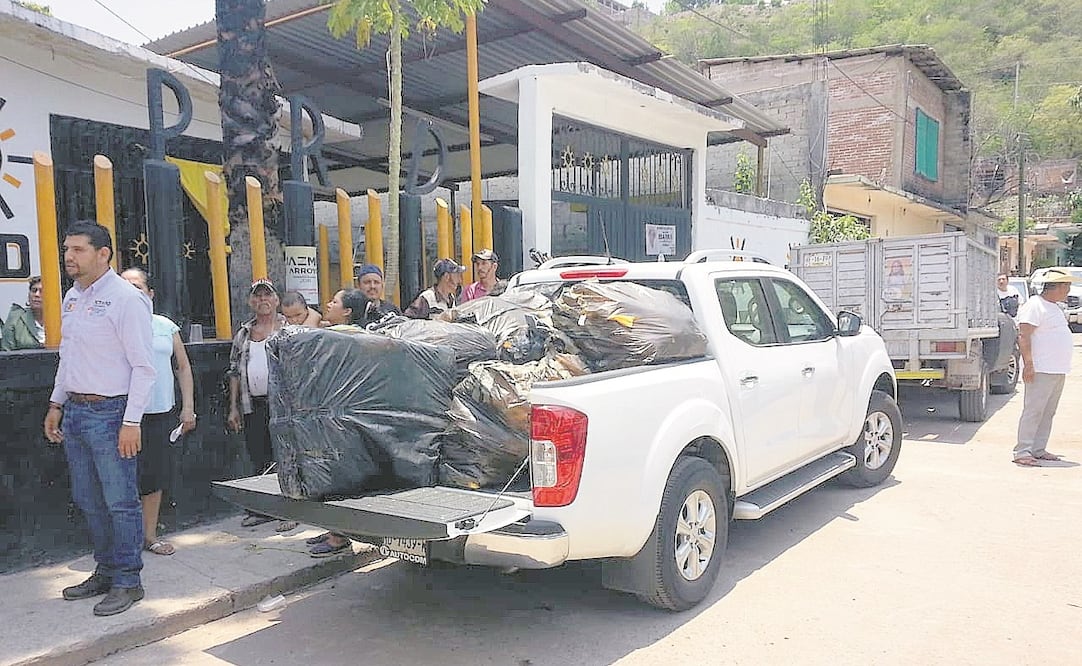 En Tuzantla una camioneta llegó a la sede del PRD, donde personas hacían fila para recibir los paquetes, en presencia del edil con licencia (izq), Octavio Ocampo. (FOTOS: CORTESÍA)