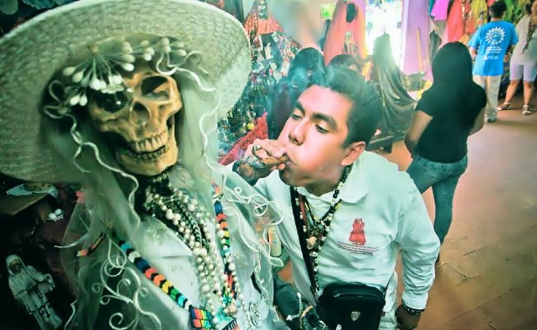 A "Saint Death" faithful blows cigar smoke on the face of a figure of the saint. (Photo: AP)