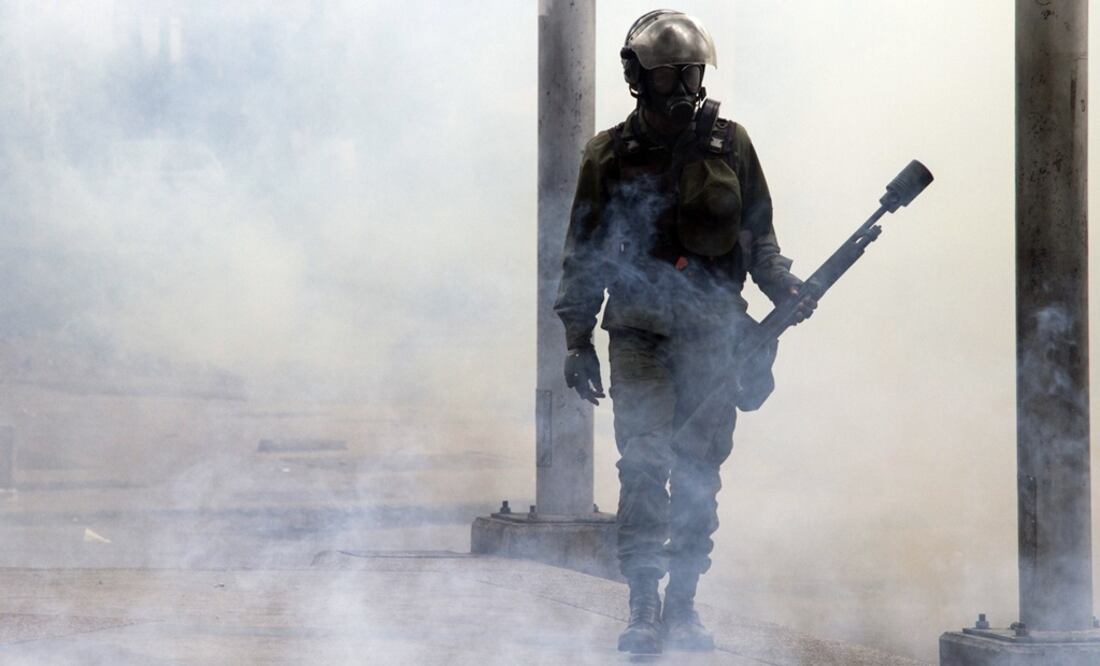 Un elemento de las fuerzas de seguridad reacciona durante un enfrentamiento en una protesta en Caracas (Foto: Xinhua)