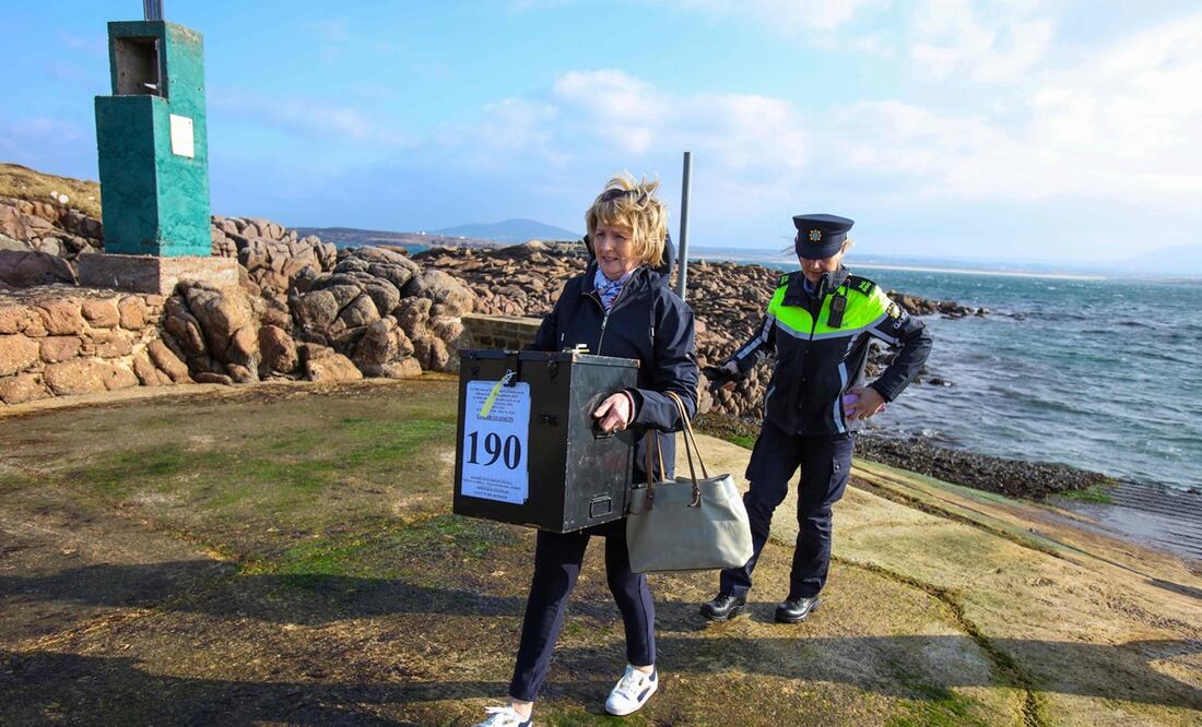 Garda Felicia Coll con la presidenta Nancy Sharkey, llega con las urnas a la isla Gola, frente a la costa de Donegal, en el oeste de Irlanda, mientras la votación en el referéndum constitucional irlandés se lleva a cabo. Foto: AFP