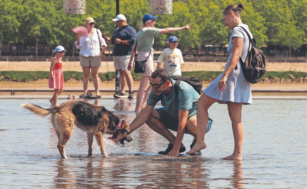 Una pareja se refresca junto con su perro en el estanque reflectante Miroir d’Eau, en Burdeos, Francia. Foto: Caroline Blumberg/ AP