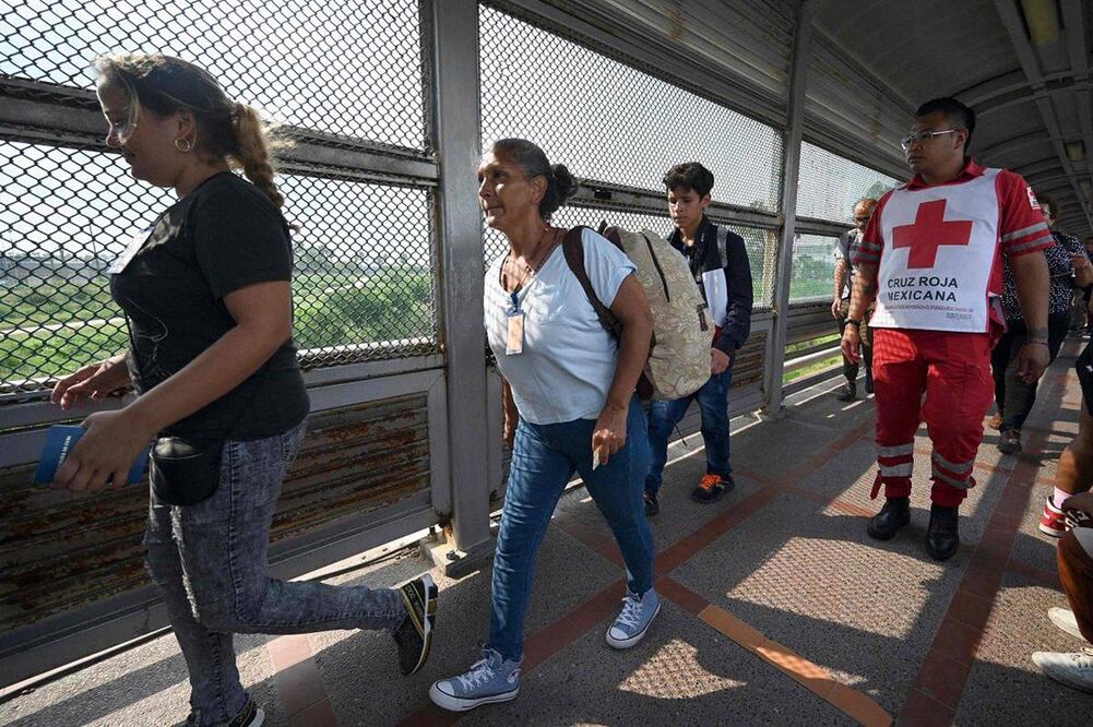Migrantes cruzan el Puente Internacional Matamoros-Brownsville tras obtener una cita para ingresar legalmente a EU. Foto: AFP
