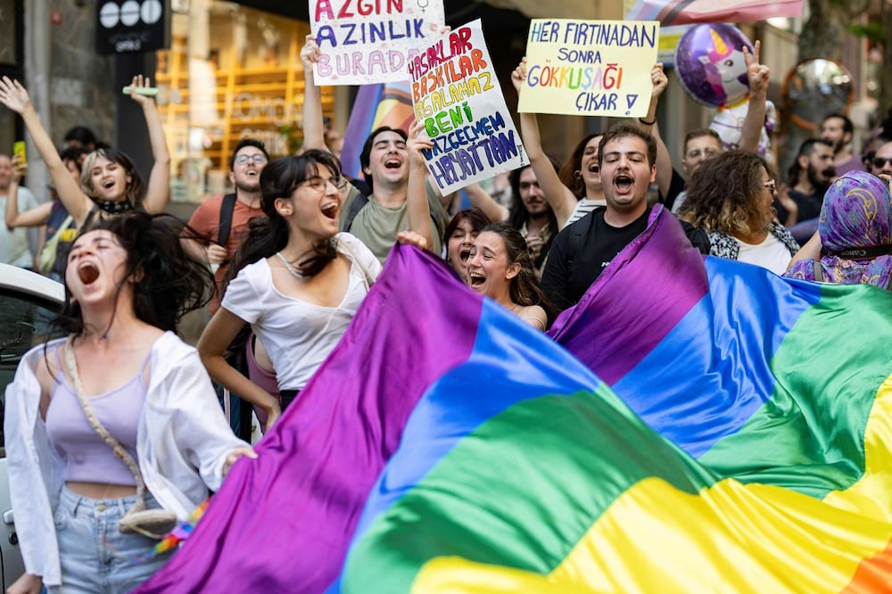 TOPSHOT - LGBTQ community members and supporters hold rainbow-colored flags and shout slogans during the unauthorized Pride March in Istanbul, on June 25, 2023. (Photo by YASIN AKGUL / AFP)