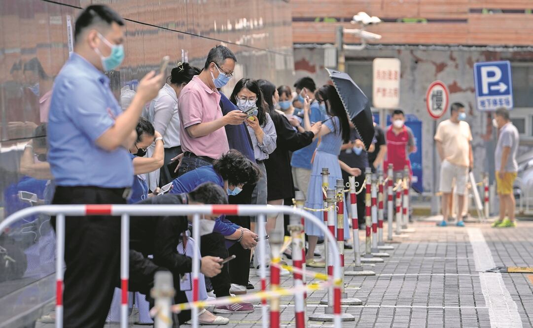 Habitantes de Beijing, mientras hacen fila para la prueba de detección de coronavirus; deben llevar mascarillas y mostrar una app en su celular para acceder a espacios públicos y facilitar el rastreo de casos. Pese a las críticas, el país mantiene su estr