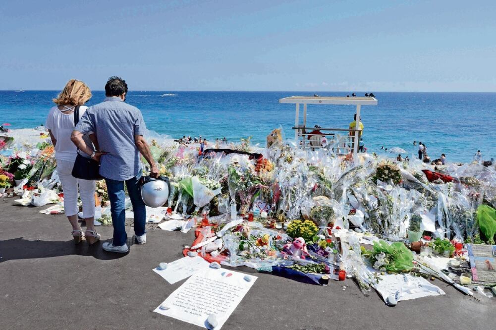 Homenaje. Paseantes se detienen ante el memorial improvisado levantado en el sitio donde el 14 de julio un hombre embistió con su camión a la multitud, en Niza (JEAN-PIERRE AMET. REUTERS)