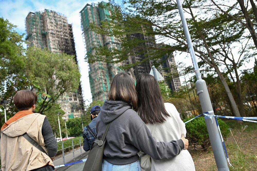Ciudadanos observan cómo quedaron los edificios de departamentos de Wang Fuk Court, tras el incendio que comenzó el miércoles pasado y dejó más de un centenar de muertos, en Hong Kong. FOTO: PETER PARKS. AFP