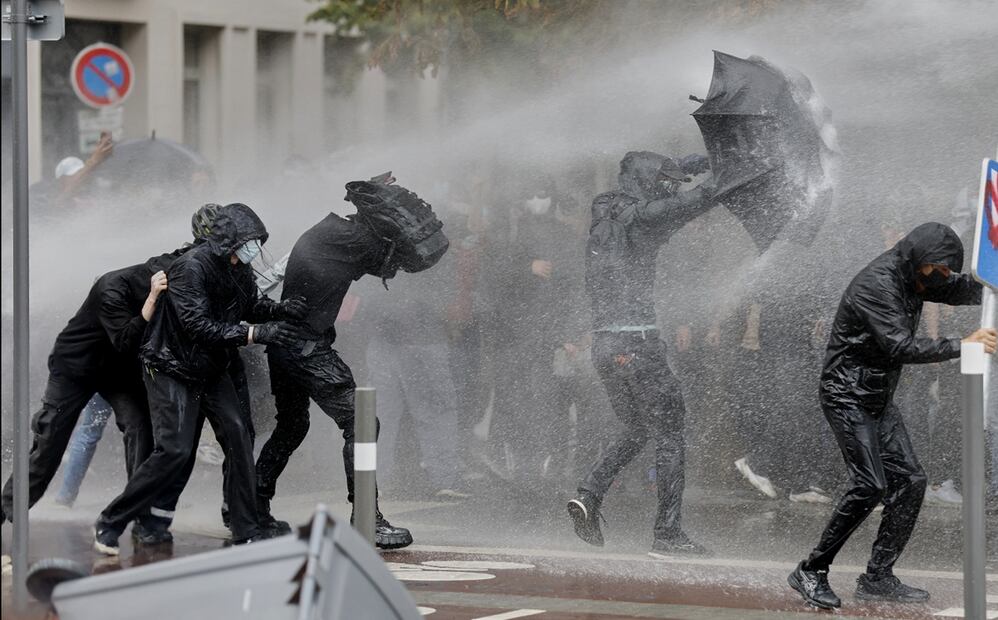 Manifestantes intentan protegerse de chorros de agua de un cañón durante una jornada de protestas en Lille, Francia, el miércoles 10 de septiembre de 2025. Foto: AP
