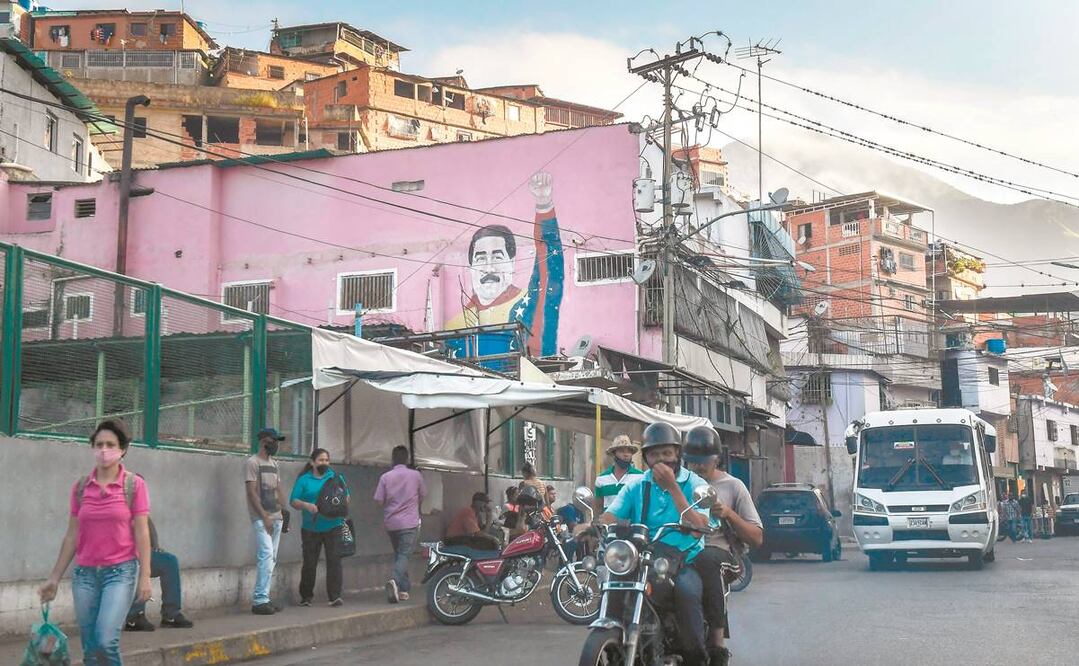 Venezolanos pasan cerca de un grafiti del presidente Nicolás Maduro en Petare, Caracas. Foto: FEDERICO PARRA. AFP