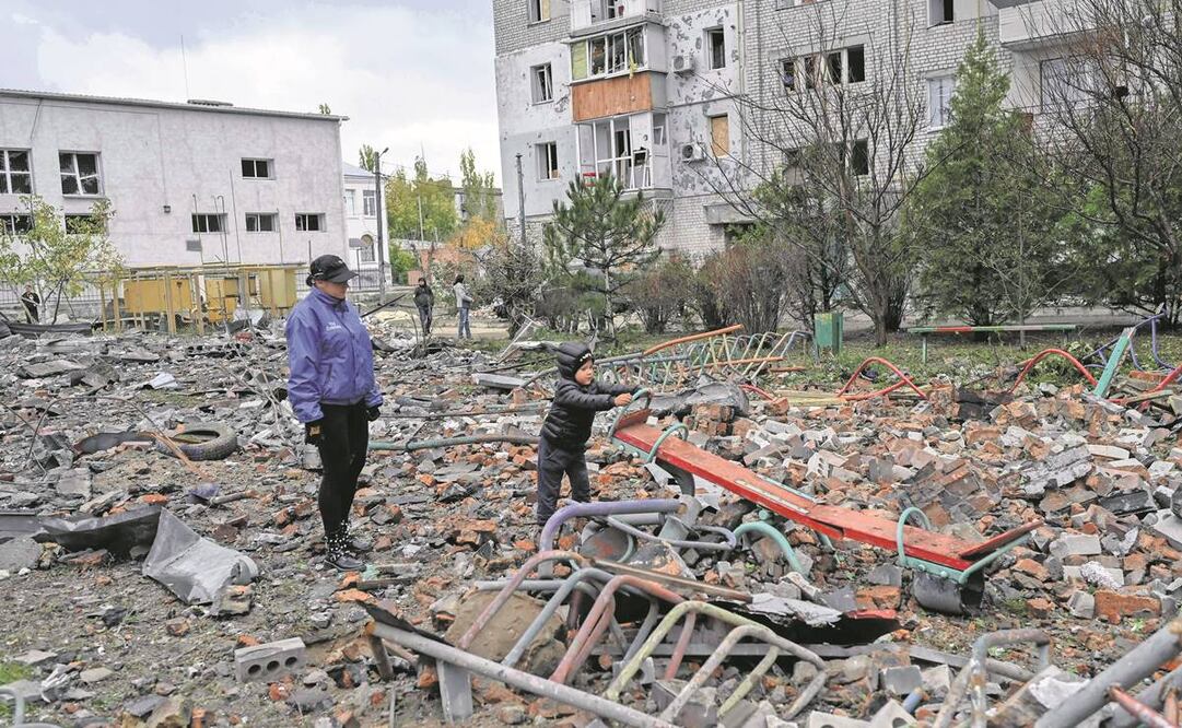 Un niño trata de jugar entre ruinas mientras su madre observa en la ciudad de Mykolaiv, Ucrania. Foto: AFP