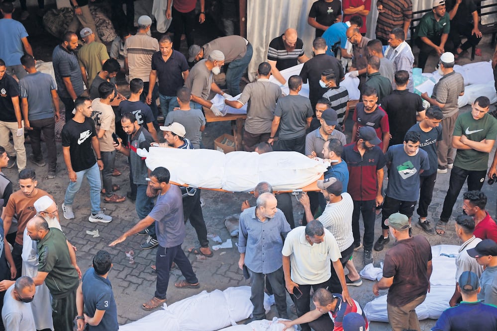 La gente saca un cuerpo amortajado del hospital al-Maamadani para enterrarlo, tras un ataque israelí en Gaza. Foto: de OMAR AL-QATTAA. AFP