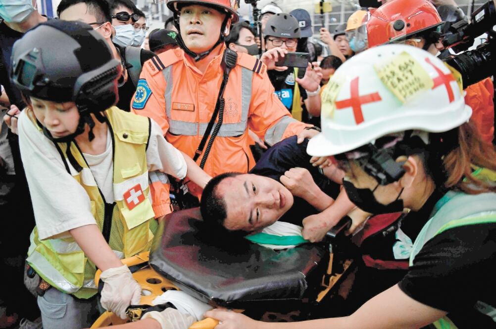 Paramédicos sacaron del aeropuerto internacional de Hong Kong a un hombre lesionado, acusado por los manifestantes de ser espía chino, ayer en las protestas. Foto: ANTHONY WALLACE. AFP