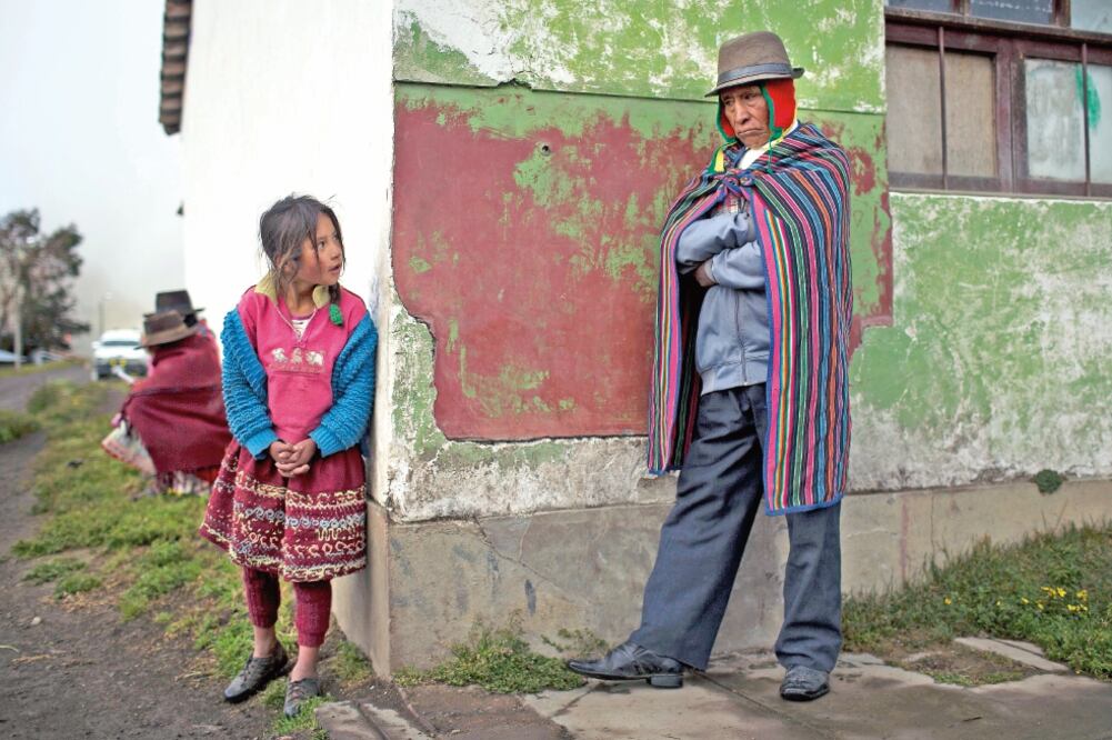 Una niña observa a un miembro de las autodefensas locales, en una reunión sobre la seguridad a desplegar en la jornada electoral de hoy en Uchuraccay, Perú (RODRIGO ABD. AP)