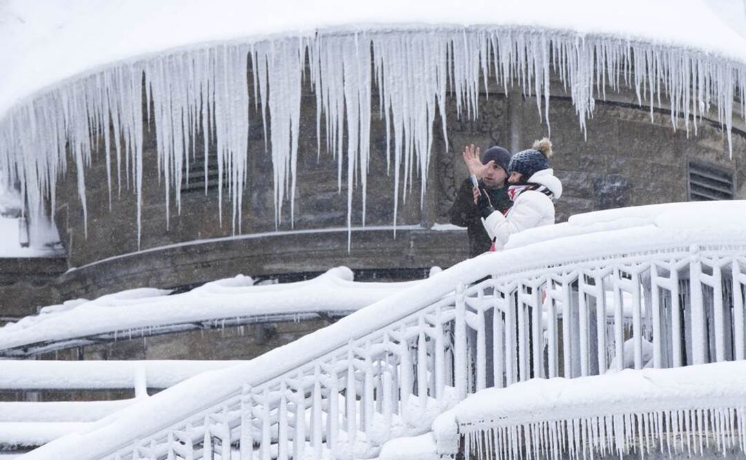 Visitantes se toman fotografías frente a un edificio cubierto con hielo y nieve, en las Cataratas del Niágara, en Ontario, Canadá. Foto: Xinhua