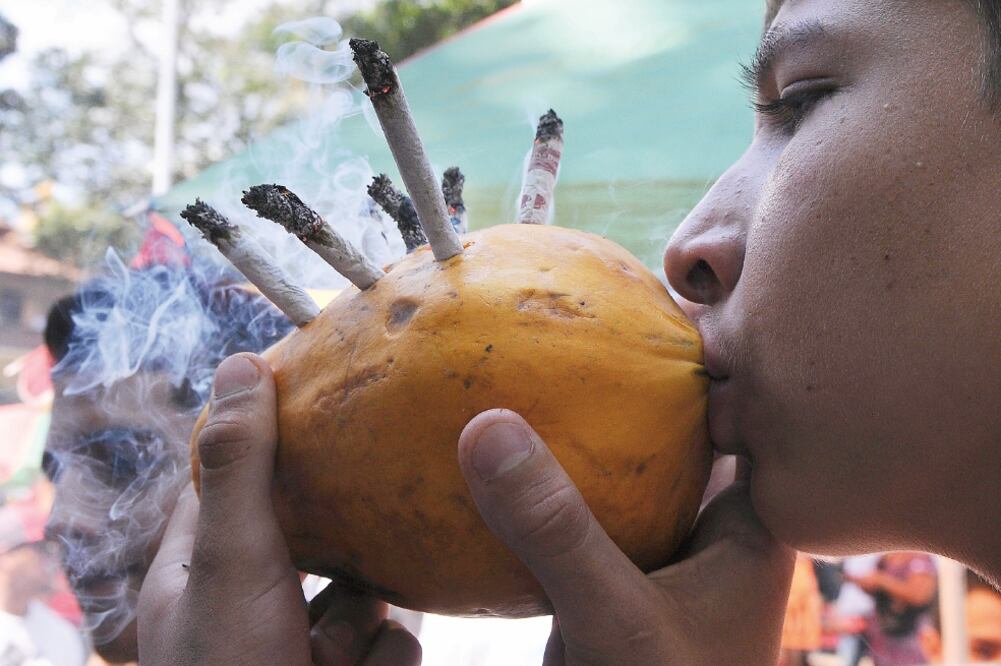 Un joven fuma cigarros de marihuana colocados en una papaya, durante una manifestación en favor de legalizar la droga, en Medellín, en mayo de 2013 (LUIS BENAVIDES. AP)